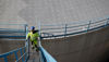 Man in yellow clothing and construction helmet walking up an oil terminal