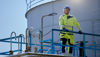 Man in yellow clothing and construction helmet looking out over an oil terminal